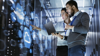 Male IT Specialist Holds Laptop and Discusses Work with Female Server Technician. They're Standing in Data Center, Rack Server Cabinet with Cloud Server Icon and Visualization.