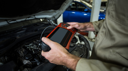 Hands of mechanic using a diagnostic tool in repair garage